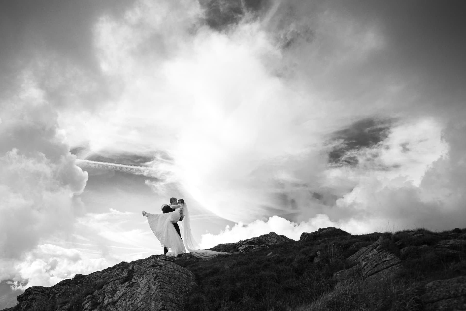 Lo sposo solleva la sposa tra le nuvole, in bianco e nero