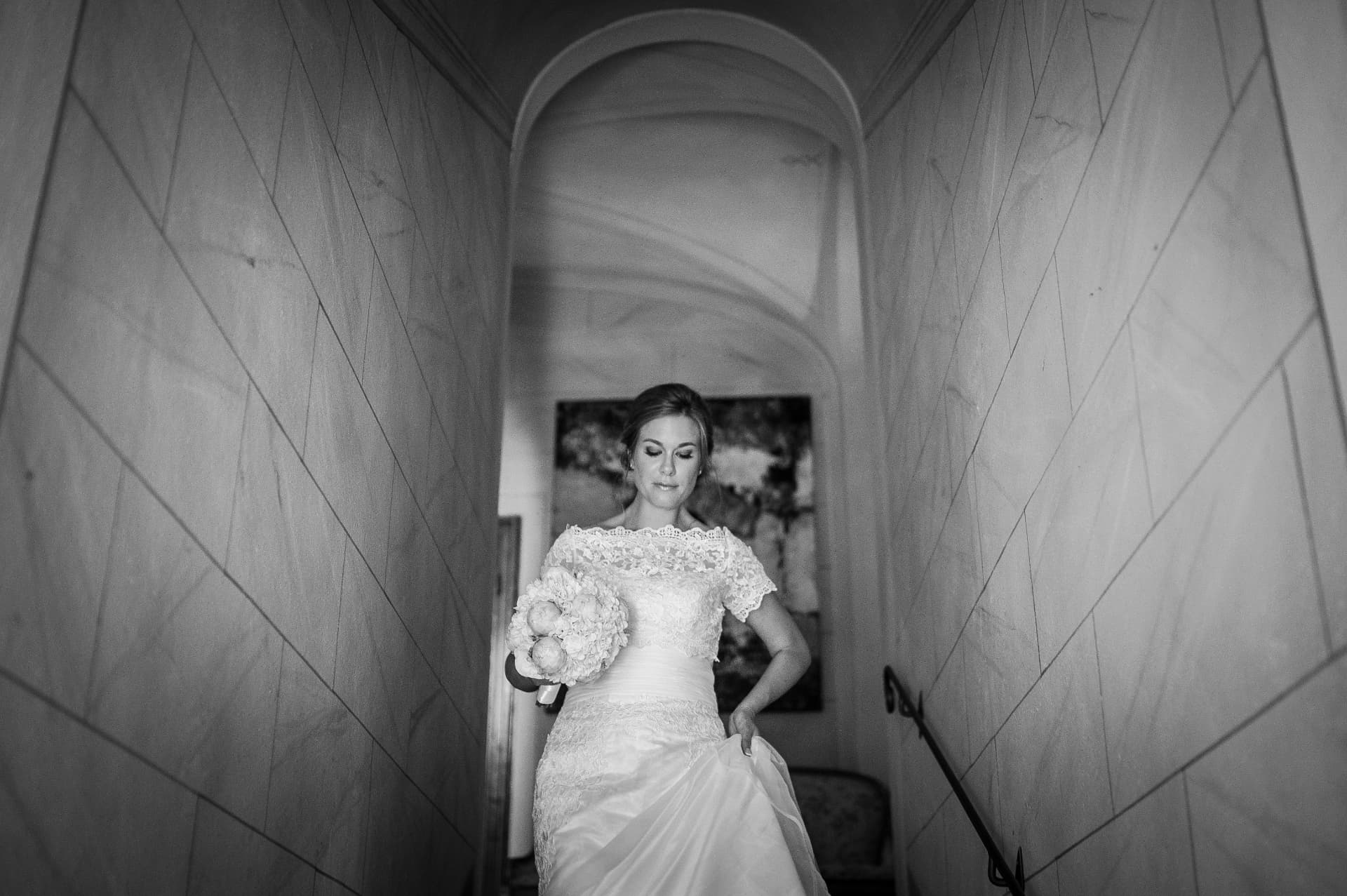 Sposa che scende una scala di marmo con il bouquet