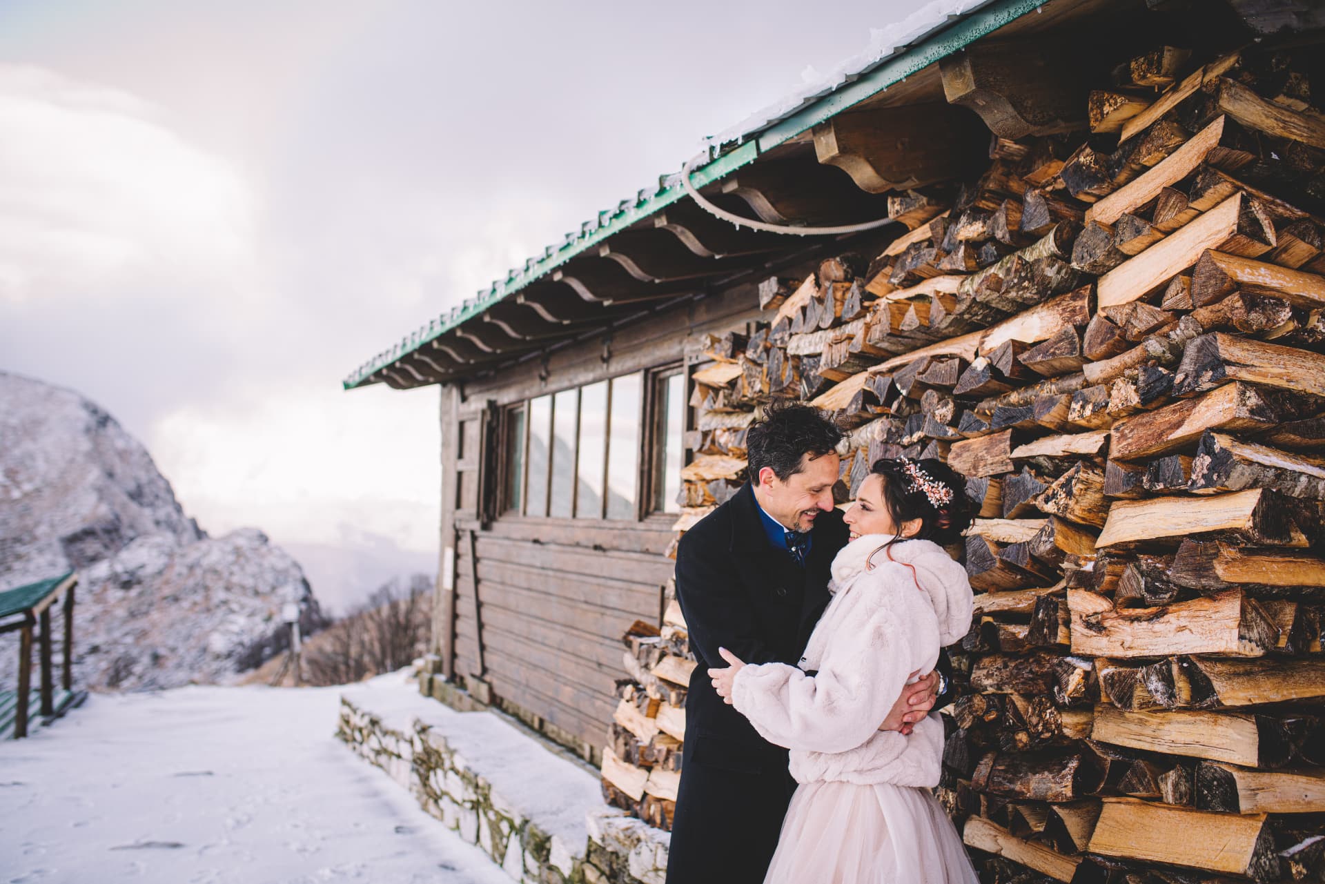 Gli sposi abbracciati accanto alla legnaia del rifugio