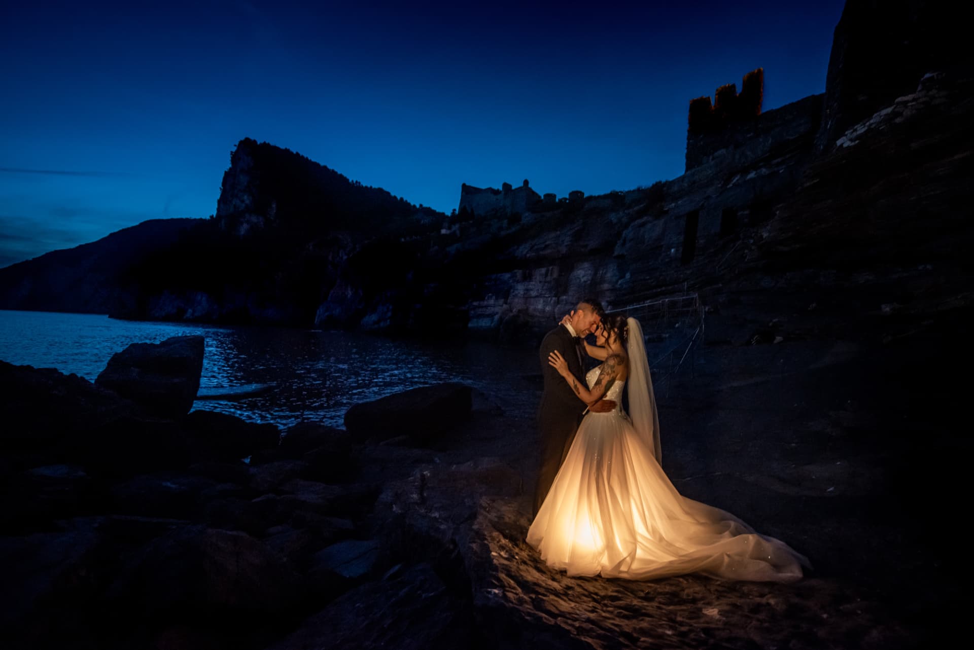 Gli sposi sulla costa di notte, l'abito della sposa illuminato dall'interno